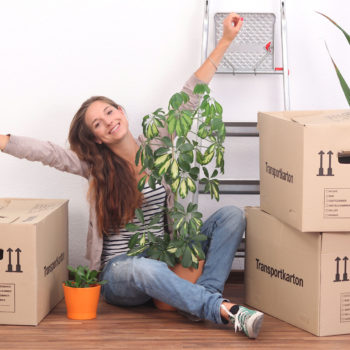 Frau in Wohnung mit gepackten Kartons - Lagerraum für Auslandsaufenthalt
